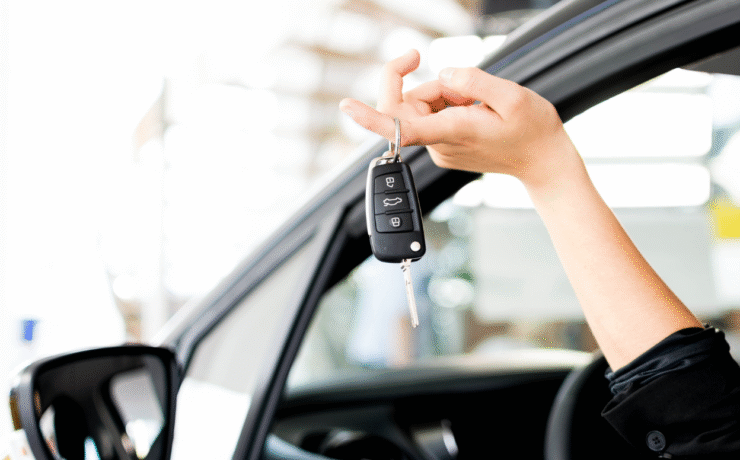 A person holding new car keys beside their vehicle, representing what to do after buying a car in Ireland.