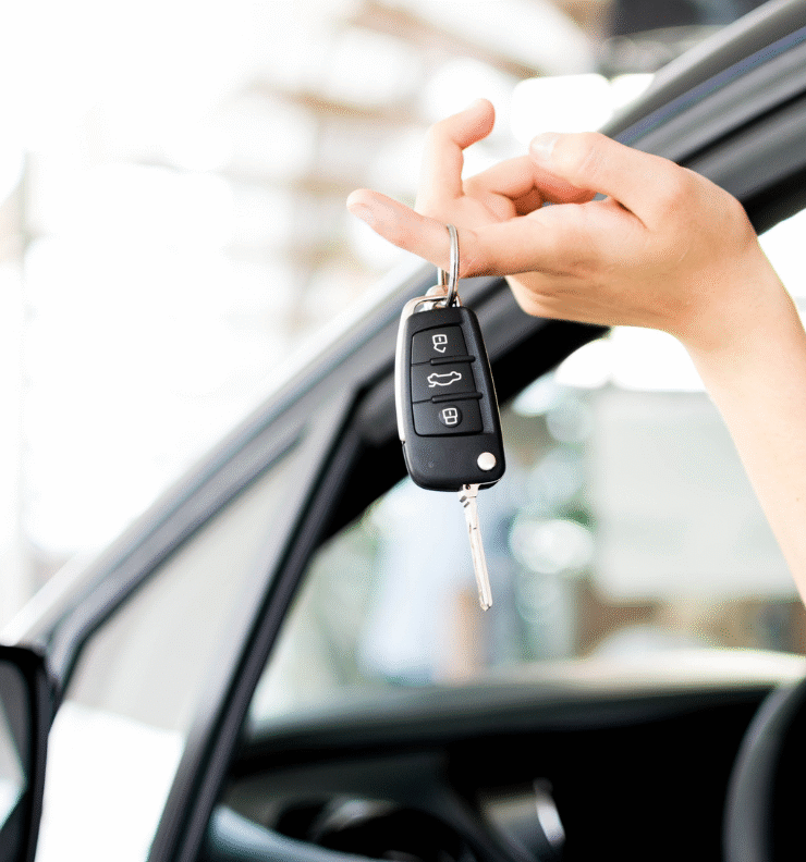 A person holding new car keys beside their vehicle, representing what to do after buying a car in Ireland.