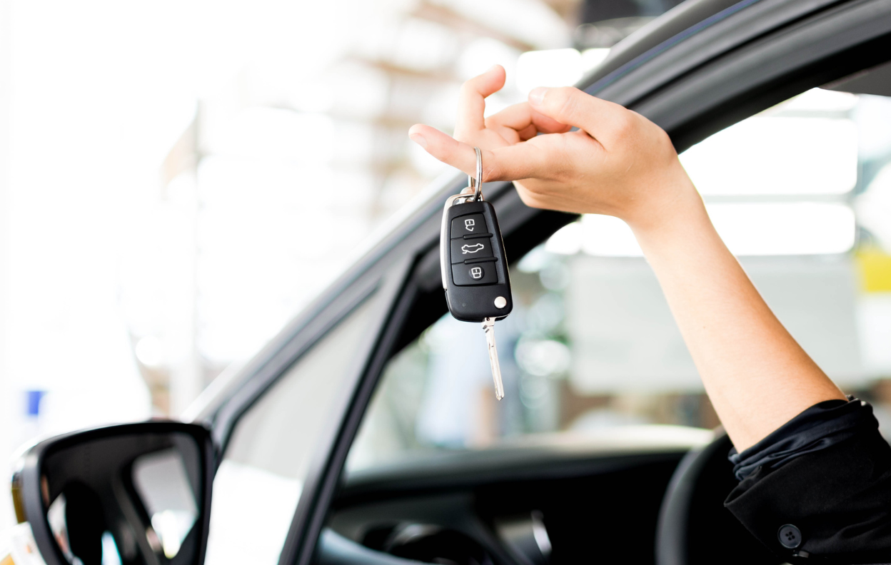 A person holding new car keys beside their vehicle, representing what to do after buying a car in Ireland.